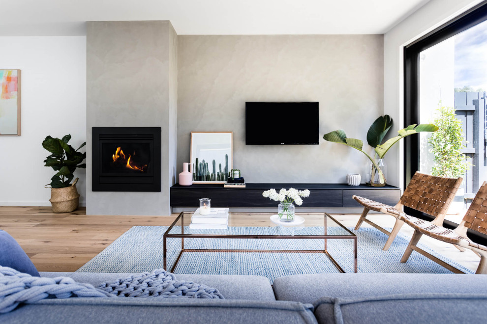 Imagen de salón abierto contemporáneo con paredes grises, suelo de madera en tonos medios, todas las chimeneas, televisor colgado en la pared y suelo marrón