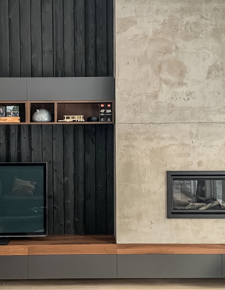 Immagine di un soggiorno minimalista aperto con pareti nere, cornice del camino in cemento e parete attrezzata