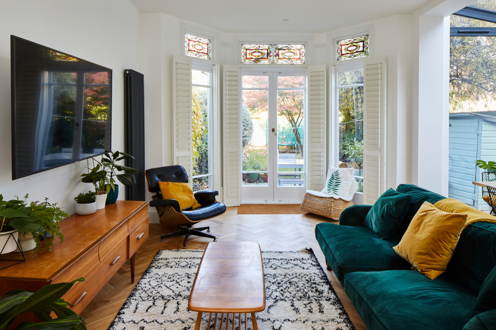 Immagine di un soggiorno design di medie dimensioni e aperto con pareti bianche, pavimento in legno massello medio e TV a parete