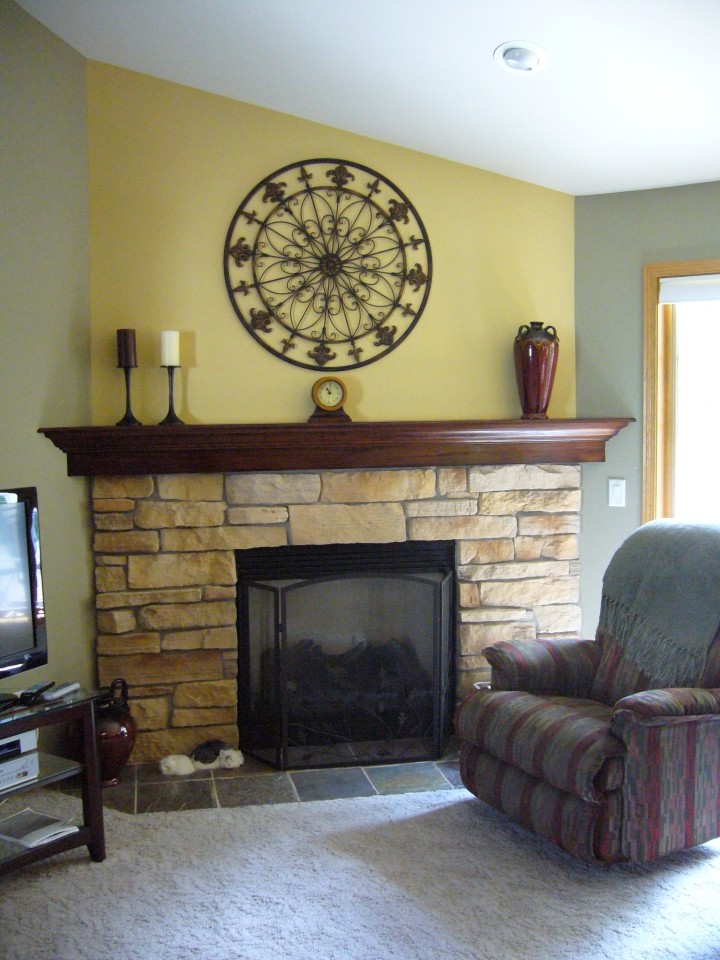Cette photo montre un petit salon chic fermé avec un mur jaune, moquette, un manteau de cheminée en pierre, une cheminée standard et un téléviseur indépendant.