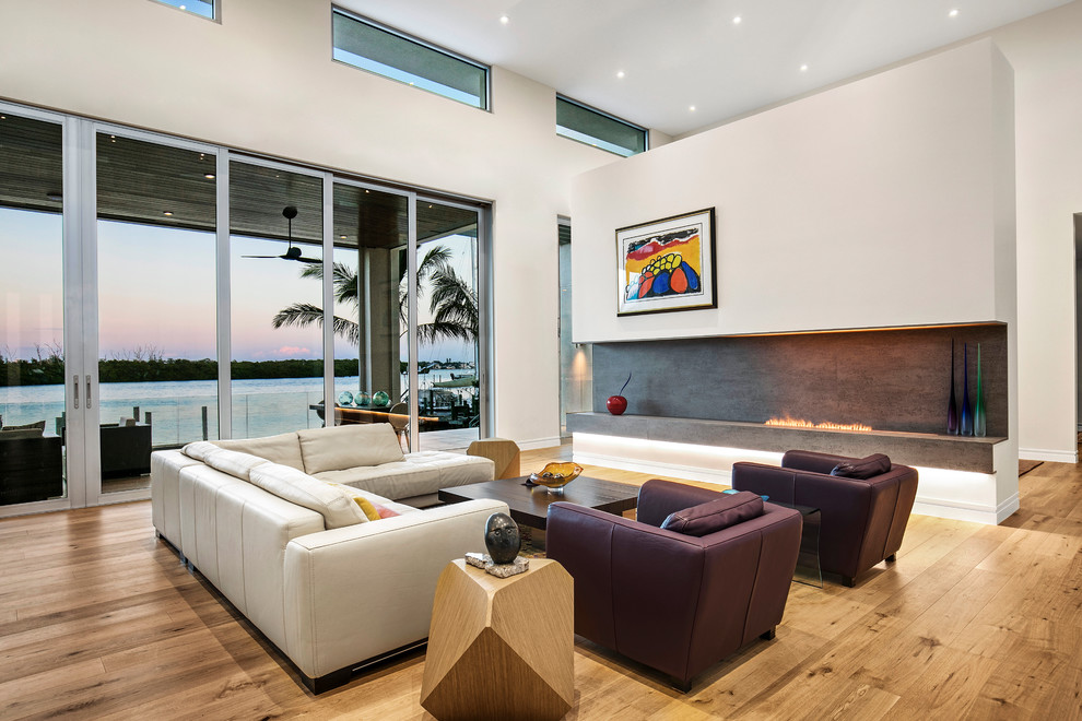 Inspiration for a modern living room in Tampa with white walls, light hardwood flooring, a ribbon fireplace and brown floors.