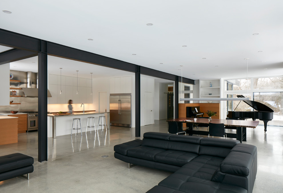 Diseño de salón abierto urbano extra grande con paredes blancas, suelo de cemento, estufa de leña, marco de chimenea de metal y suelo gris