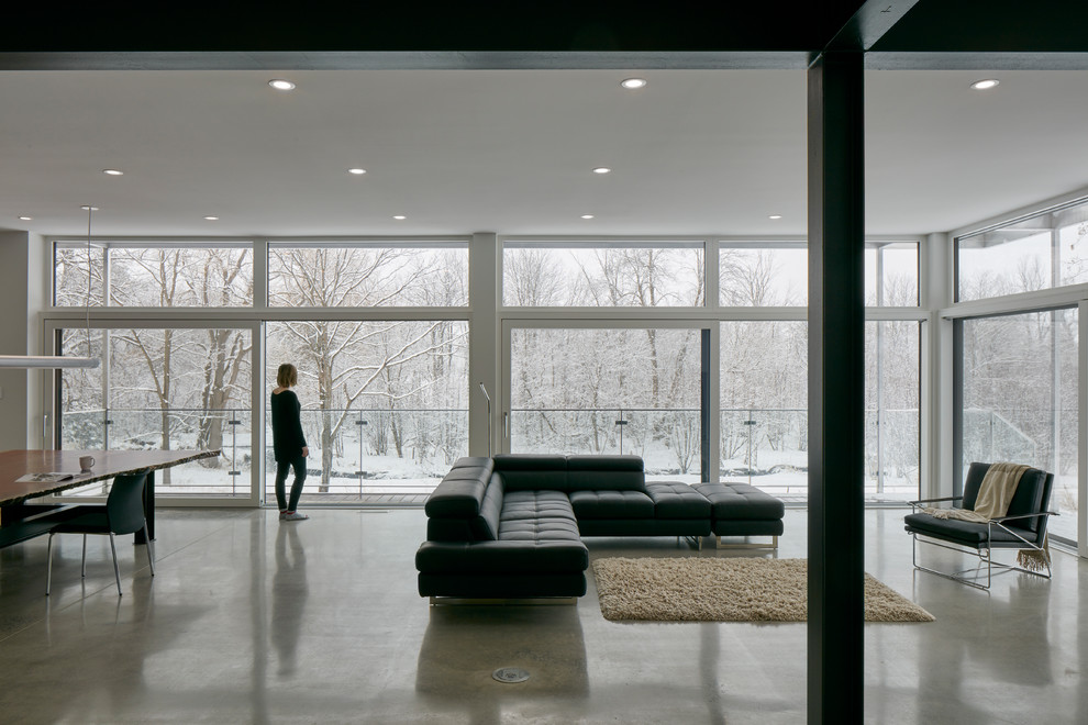 Geräumiges, Offenes Industrial Wohnzimmer mit weißer Wandfarbe, Betonboden, Kaminofen, Kaminumrandung aus Metall und grauem Boden in Ottawa