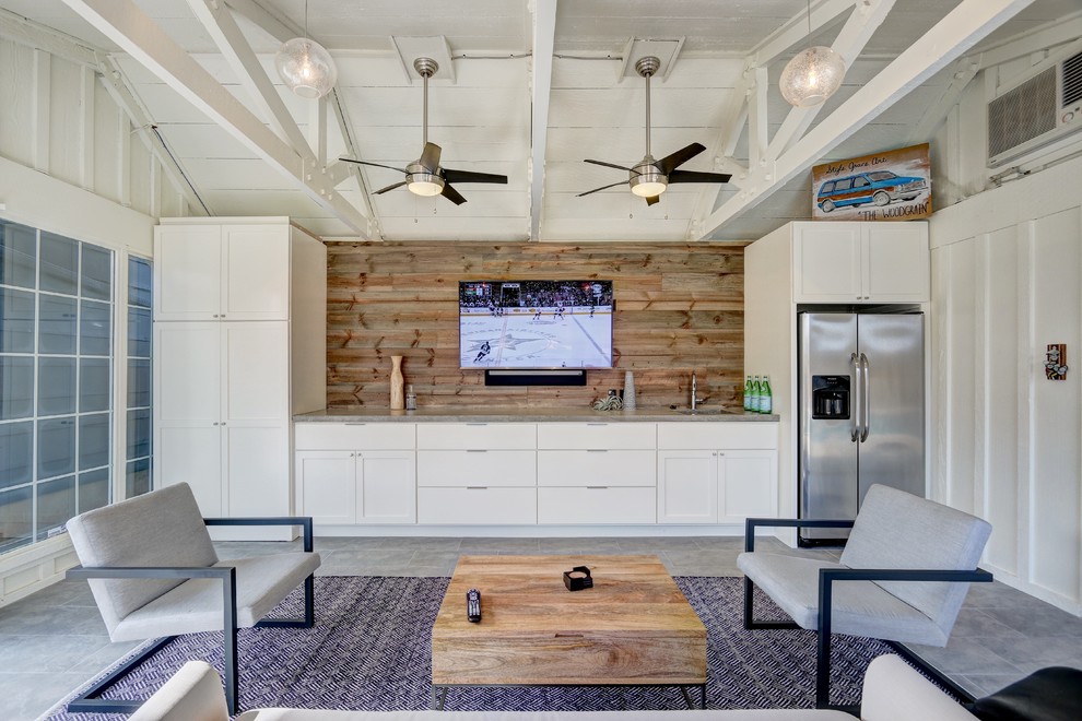 Example of a large beach style enclosed concrete floor living room design in Oklahoma City with white walls, no fireplace and a wall-mounted tv