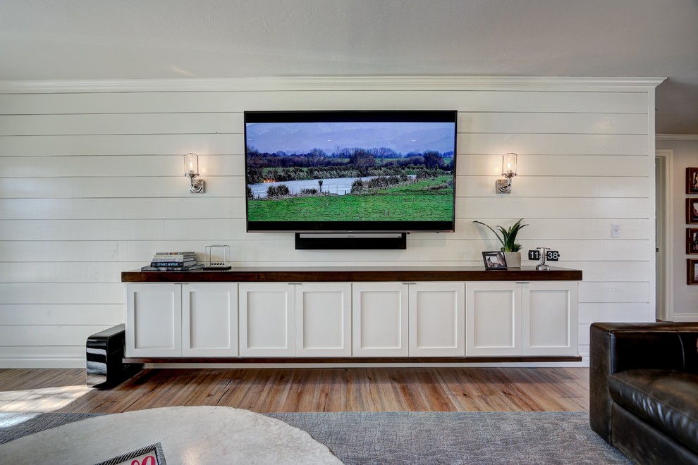 Ispirazione per un grande soggiorno tradizionale aperto con pareti bianche, pavimento in legno massello medio e TV a parete