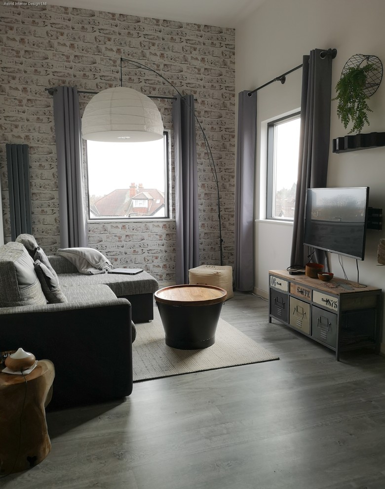 This is an example of a small industrial formal enclosed living room in London with white walls, a freestanding tv and grey floors.