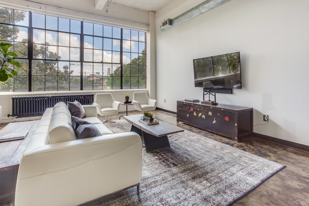 Foto di un soggiorno industriale aperto con pareti bianche, pavimento in cemento e TV a parete