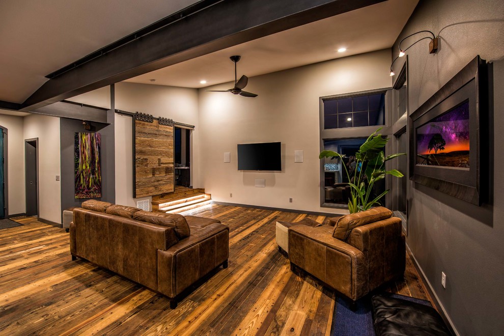 Foto di un soggiorno industriale di medie dimensioni e aperto con pareti beige, pavimento in legno massello medio e TV a parete