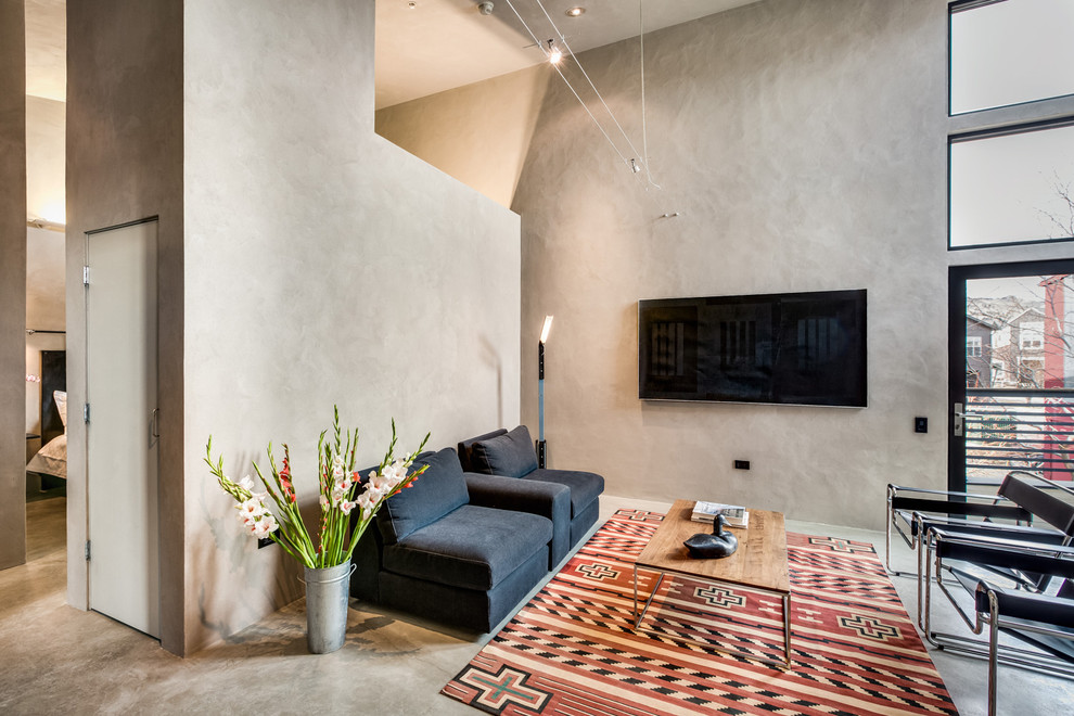 Пример оригинального дизайна: открытая гостиная комната в стиле лофт с серыми стенами, телевизором на стене и серым полом