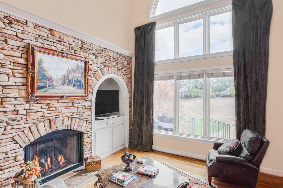 Photo of a classic open plan living room with beige walls, carpet, a standard fireplace, a brick fireplace surround and grey floors.