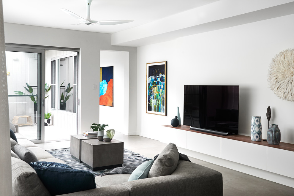 This is an example of a large contemporary living room in Sydney with white walls, a freestanding tv and grey floors.