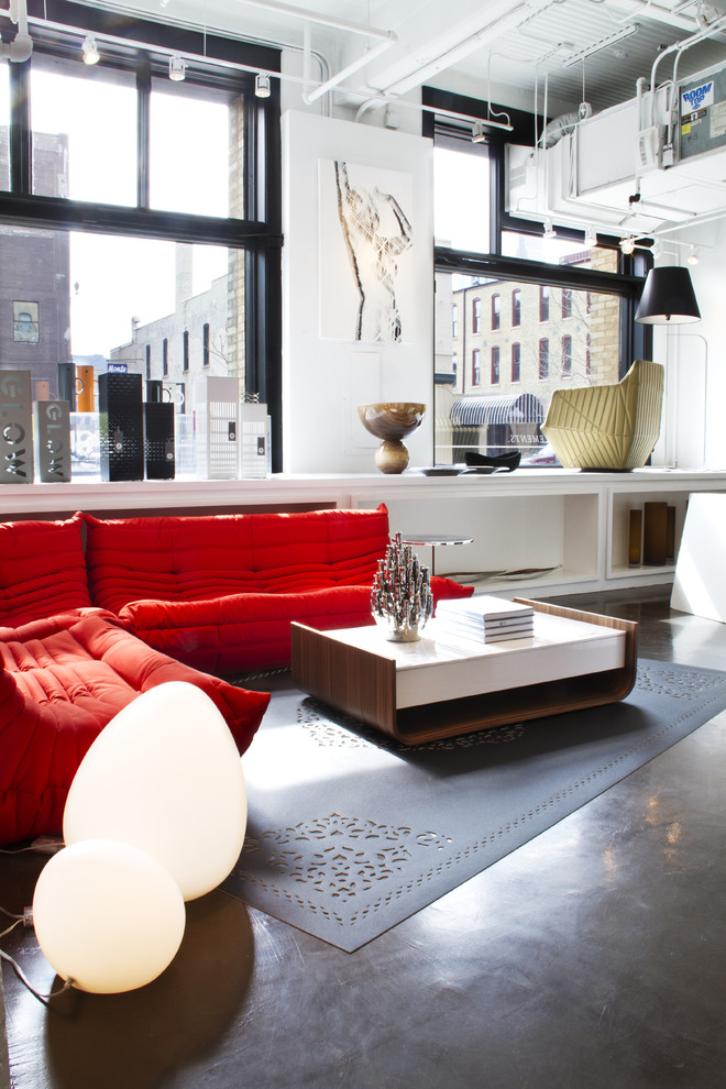 ミネアポリスにあるコンテンポラリースタイルのおしゃれなリビング (コンクリートの床、赤いソファ) の写真