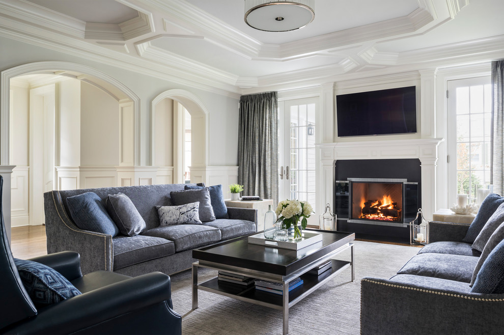 Klassisches Wohnzimmer mit weißer Wandfarbe, braunem Holzboden, Kamin, TV-Wand, braunem Boden und Kaminumrandung aus Stein in New York