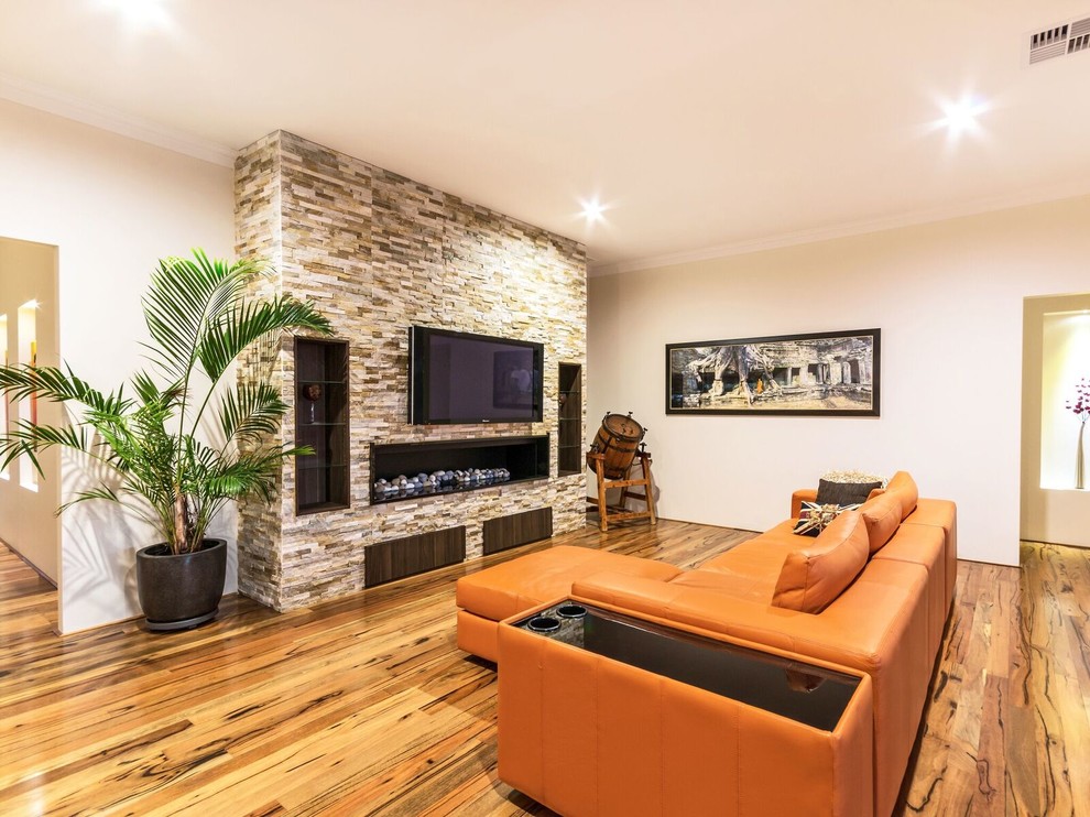 Offenes Country Wohnzimmer mit beiger Wandfarbe, dunklem Holzboden, Kamin, Kaminumrandung aus Stein und TV-Wand in Perth