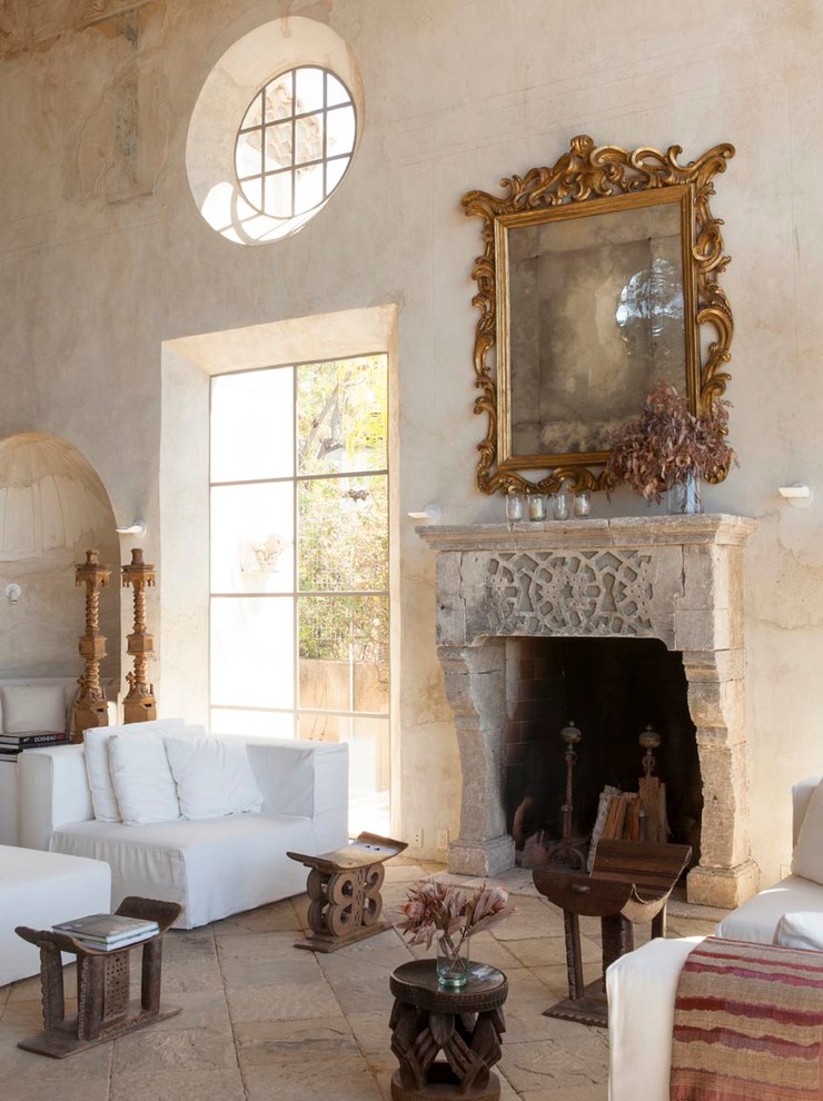 This is an example of a large mediterranean formal open plan living room in Los Angeles with limestone flooring, a standard fireplace, a stone fireplace surround, no tv and beige walls.