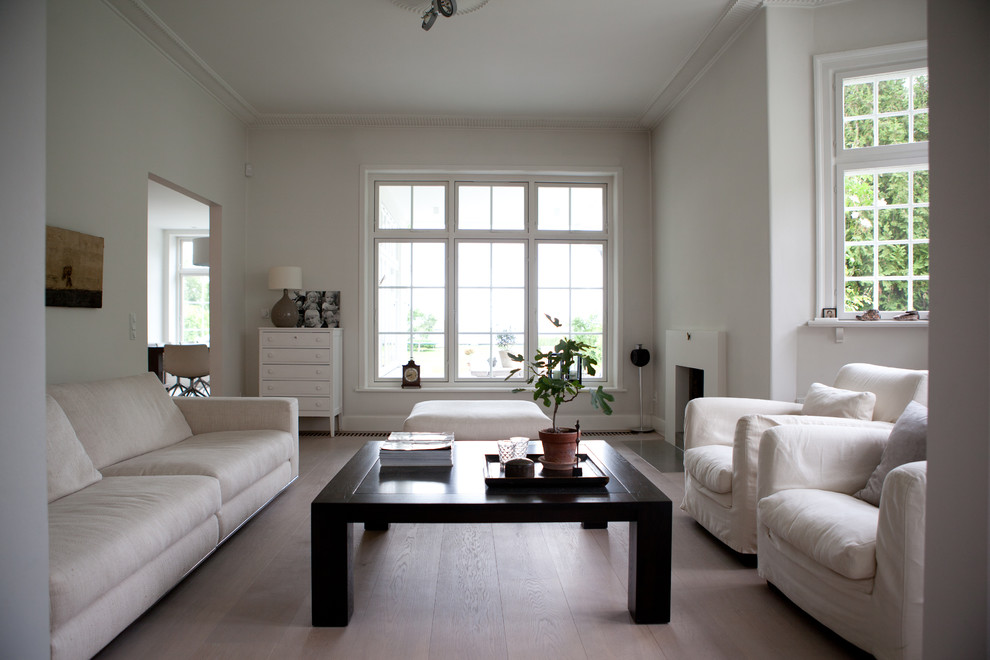 Photo of a classic living room in Amsterdam with white walls, light hardwood flooring and a standard fireplace.