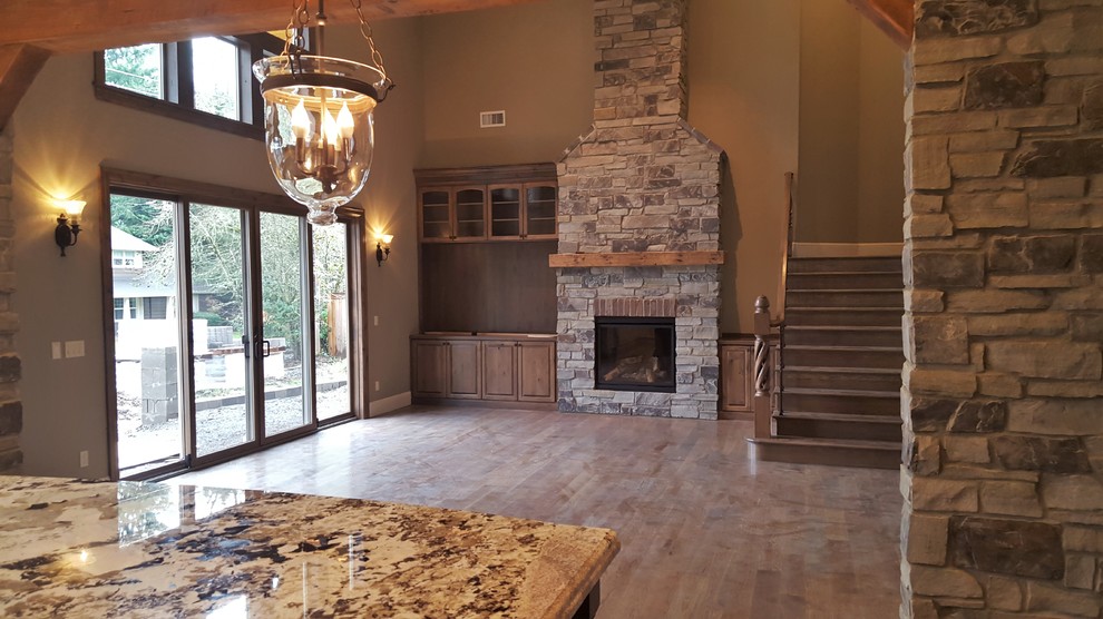 Photo of a large open plan living room in Portland with medium hardwood flooring, a standard fireplace, a wooden fireplace surround and a built-in media unit.