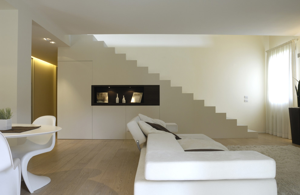Cette image montre un salon design ouvert avec un mur blanc et parquet clair.