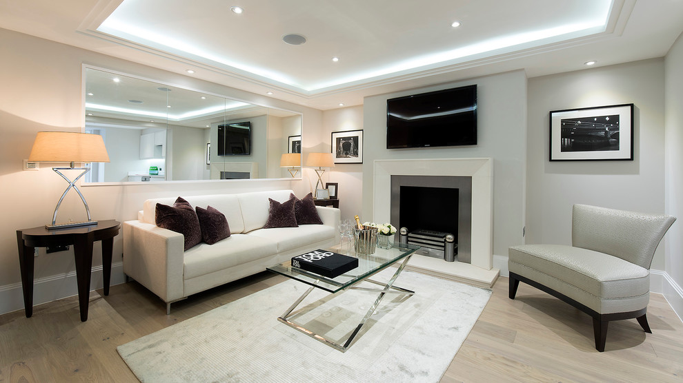 Стильный дизайн: гостиная комната в современном стиле с светлым паркетным полом, стандартным камином и телевизором на стене - последний тренд