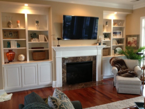Esempio di un grande soggiorno minimalista aperto con pareti beige, parquet scuro, camino classico, cornice del camino in legno e TV a parete