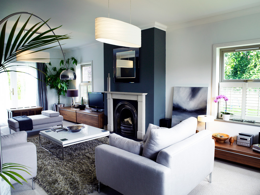 This is an example of a contemporary open plan living room in Other with grey walls, carpet, a wood burning stove, a wooden fireplace surround and a freestanding tv.