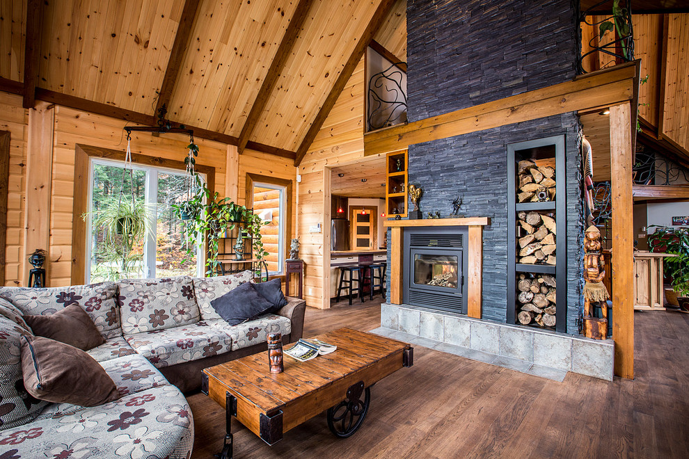 Offenes Rustikales Wohnzimmer mit brauner Wandfarbe, braunem Holzboden, Kaminofen und Kaminumrandung aus Stein in Edmonton