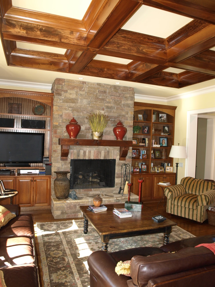 Mittelgroßes, Offenes Klassisches Wohnzimmer mit gelber Wandfarbe, braunem Holzboden, Kamin, Kaminumrandung aus Stein und Multimediawand in Charlotte