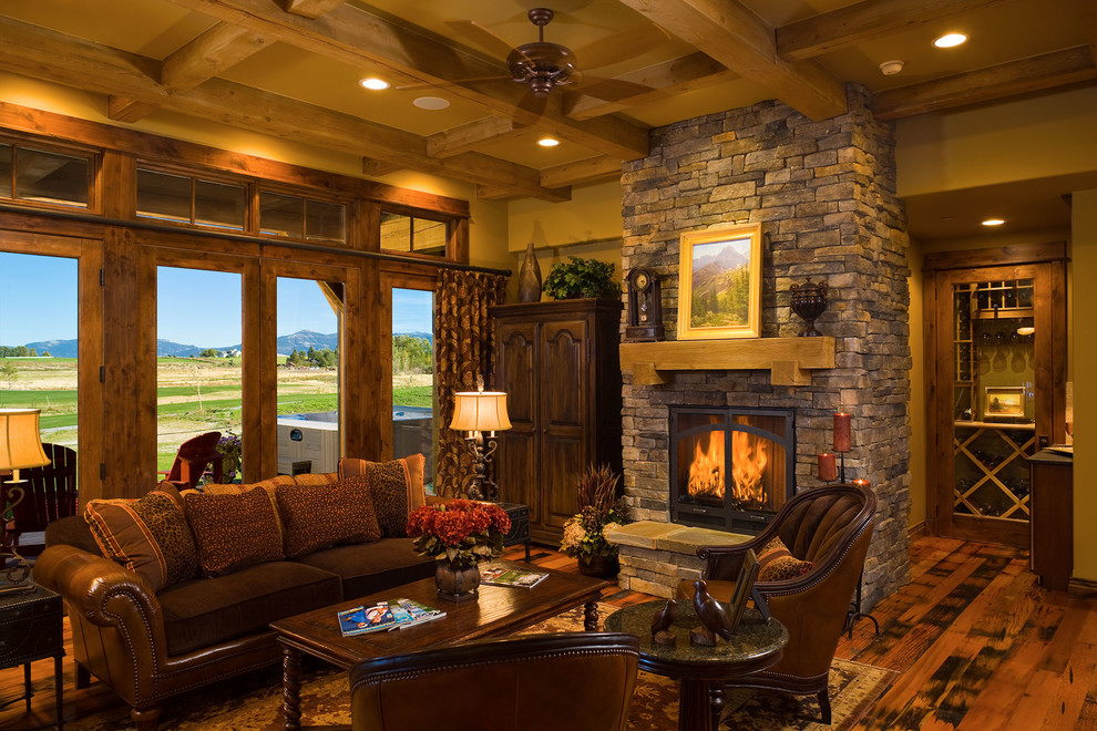 Example of a mid-sized mountain style formal and enclosed medium tone wood floor and brown floor living room design in Other with beige walls, a standard fireplace, a stone fireplace and no tv