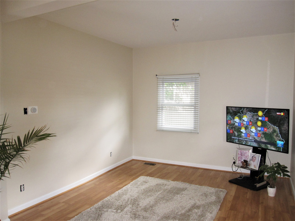 Modelo de salón para visitas abierto actual grande sin chimenea con paredes beige, suelo laminado, televisor independiente y suelo marrón