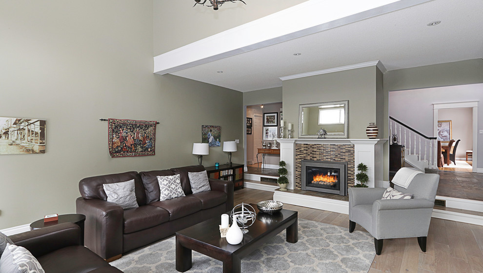 Idée de décoration pour un grand salon design avec un mur vert, parquet clair, une cheminée standard et un manteau de cheminée en bois.
