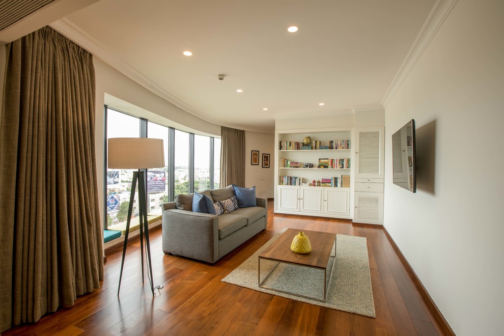 Ejemplo de sala de estar cerrada clásica renovada con paredes beige, suelo de madera en tonos medios, televisor colgado en la pared y suelo marrón