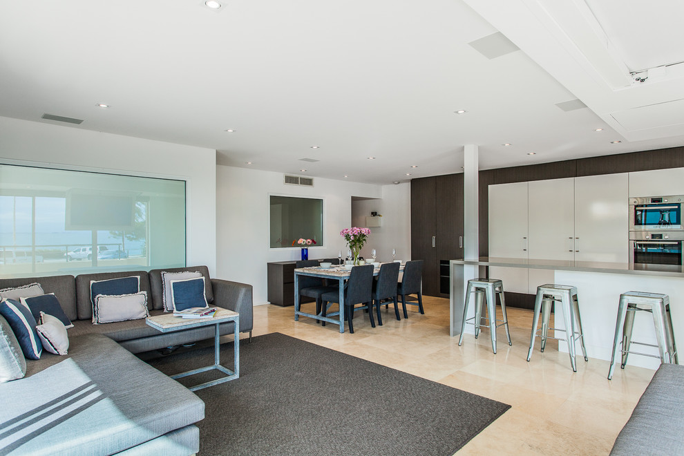 Стильный дизайн: парадная, открытая гостиная комната в современном стиле с белыми стенами, скрытым телевизором и бежевым полом - последний тренд