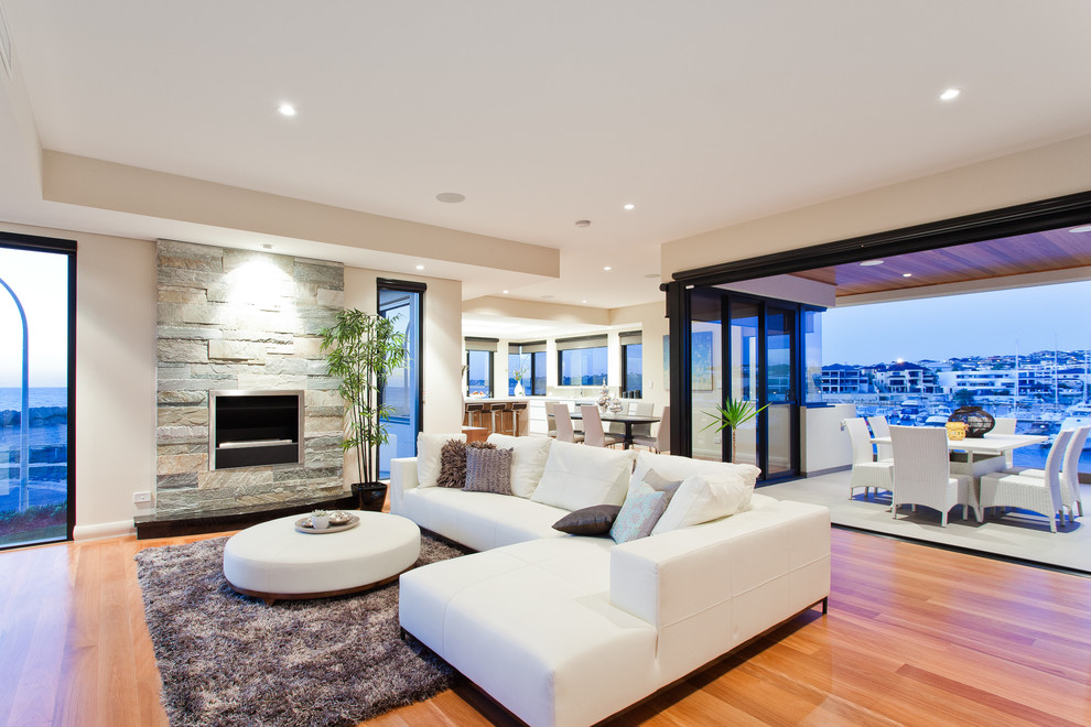 Offenes Modernes Wohnzimmer mit beiger Wandfarbe, braunem Holzboden, Kamin und Kaminumrandung aus Stein in Perth