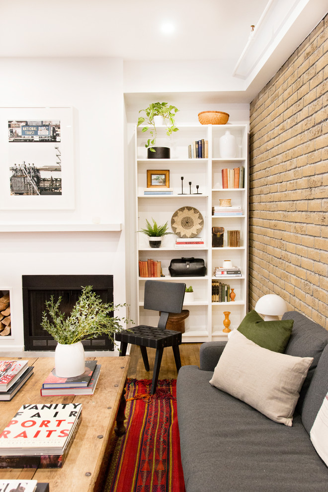 Idée de décoration pour un salon design avec une bibliothèque ou un coin lecture, un mur blanc, un sol en bois brun, une cheminée standard et un sol marron.