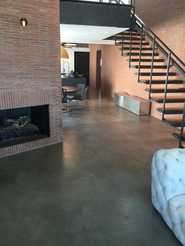 Großes, Repräsentatives Industrial Wohnzimmer im Loft-Stil mit roter Wandfarbe, Betonboden, Kamin, Kaminumrandung aus Backstein und grauem Boden in Los Angeles