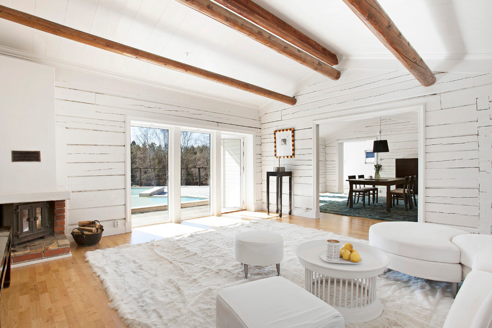 Inspiration för stora lantliga separata vardagsrum, med vita väggar, ljust trägolv, en öppen hörnspis och en spiselkrans i tegelsten