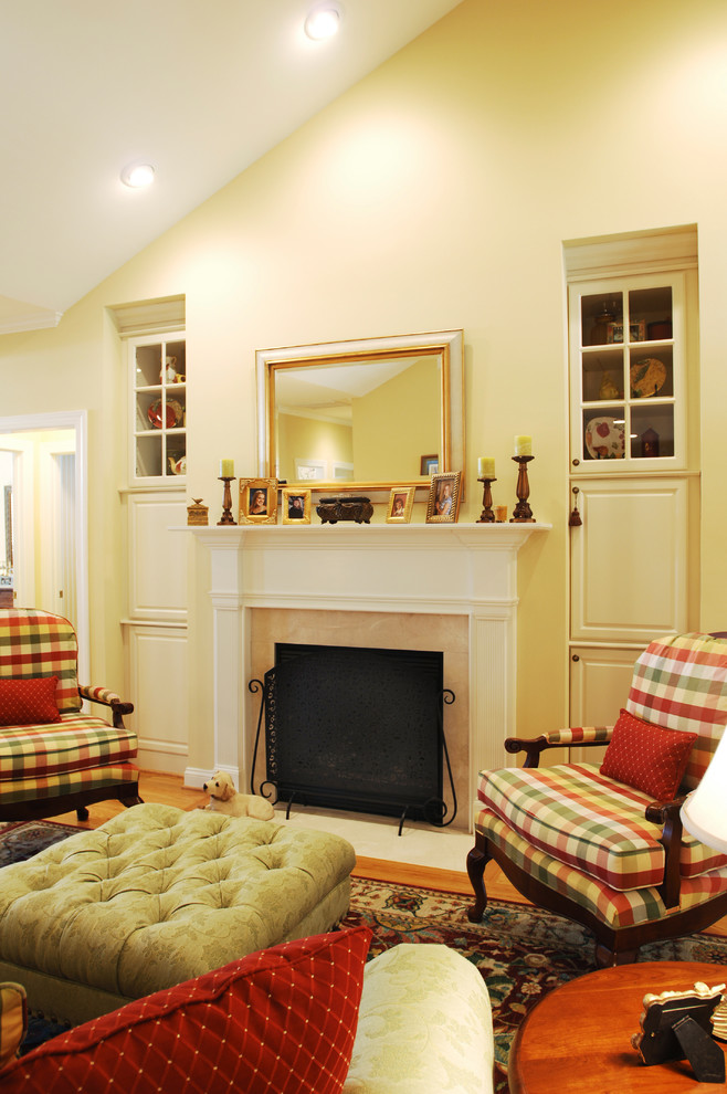 Small classic open plan living room in DC Metro with yellow walls, light hardwood flooring and a standard fireplace.