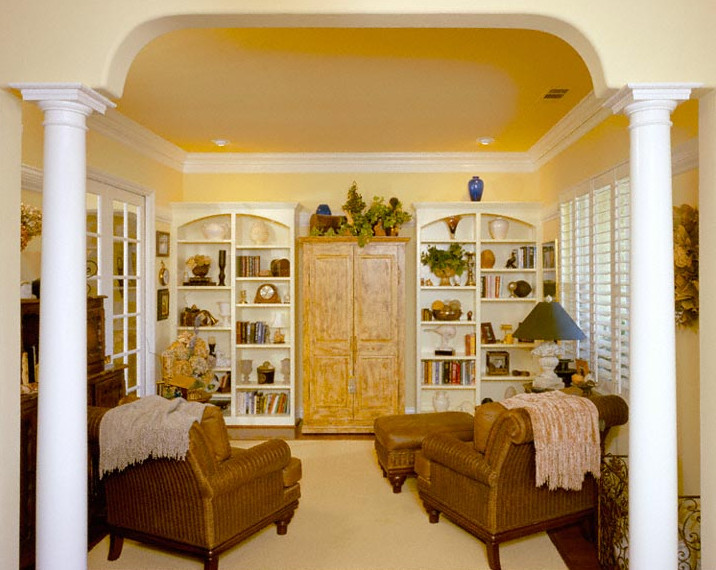 Cette photo montre un salon chic de taille moyenne et ouvert avec une bibliothèque ou un coin lecture, un mur jaune, moquette, aucune cheminée et un téléviseur fixé au mur.