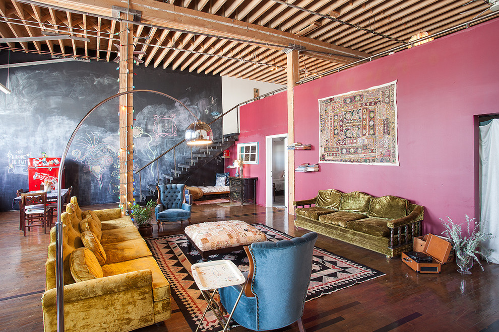 На фото: открытая гостиная комната в стиле фьюжн с розовыми стенами и темным паркетным полом с