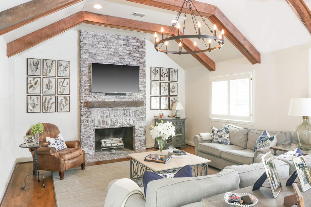 Foto di un soggiorno country con pareti bianche, pavimento in legno massello medio, camino classico, TV a parete e pavimento marrone