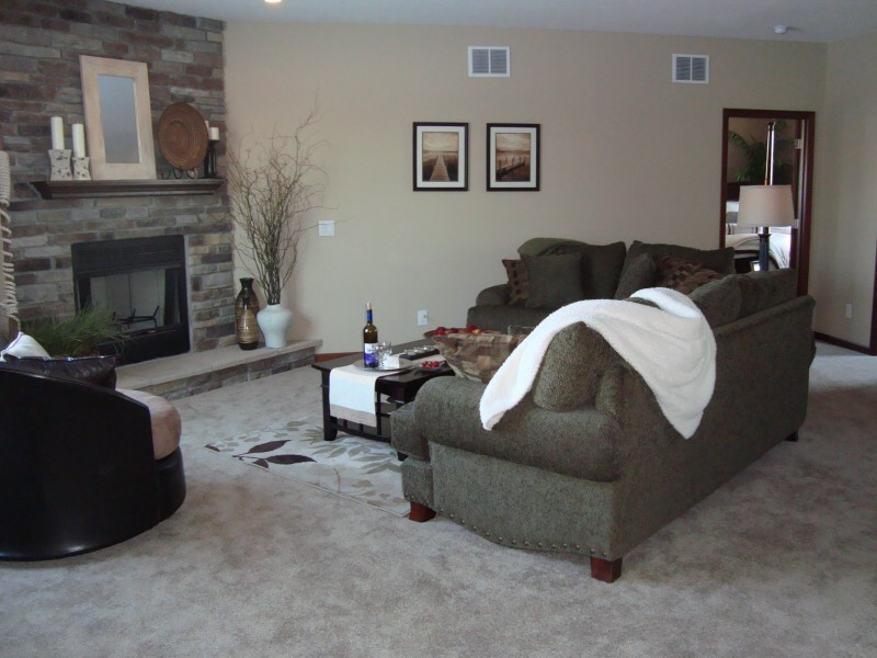 Modernes Wohnzimmer mit beiger Wandfarbe, Teppichboden, Eckkamin und Kaminumrandung aus Stein in Indianapolis