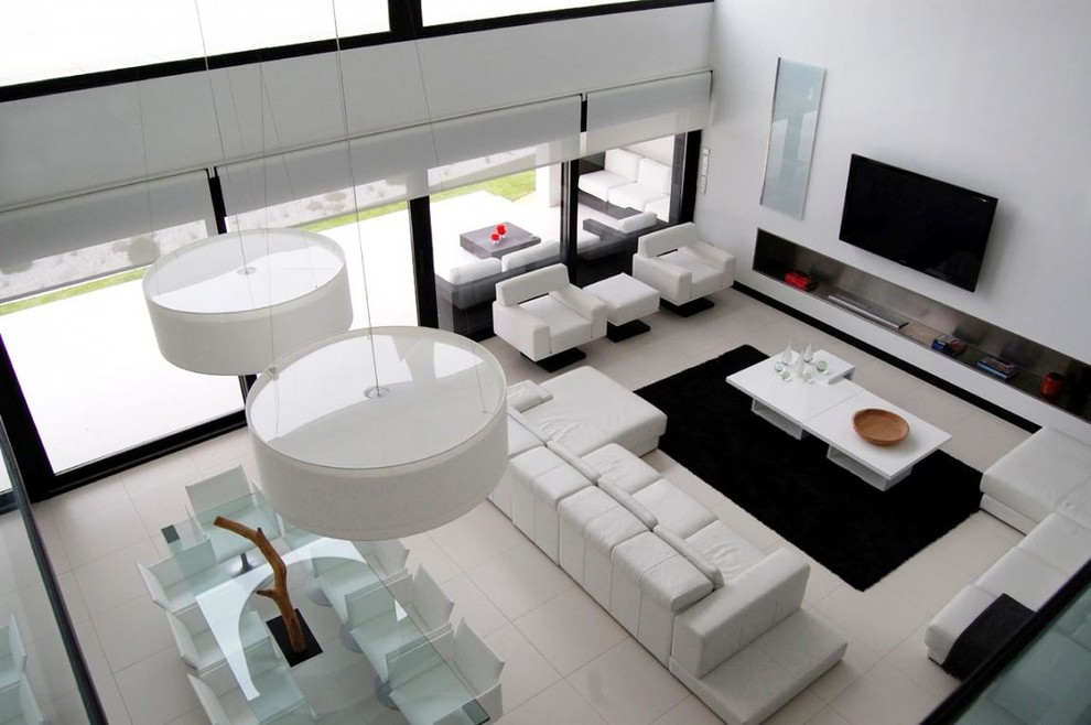 Modelo de salón abierto contemporáneo grande con paredes blancas, suelo de baldosas de cerámica y televisor colgado en la pared