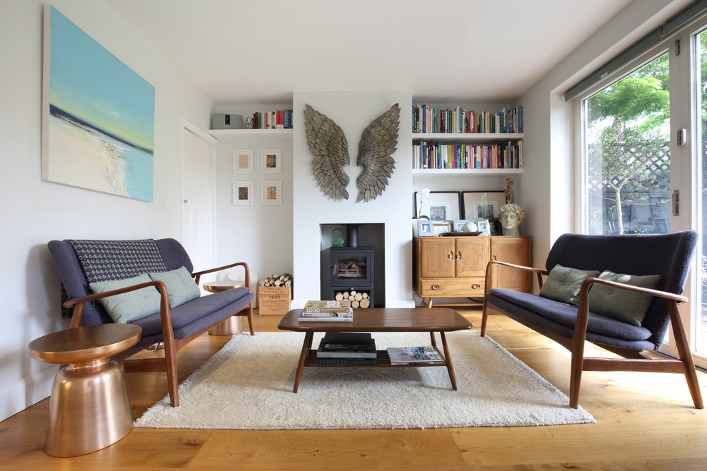 Modelo de salón nórdico de tamaño medio sin televisor con suelo de madera clara y estufa de leña