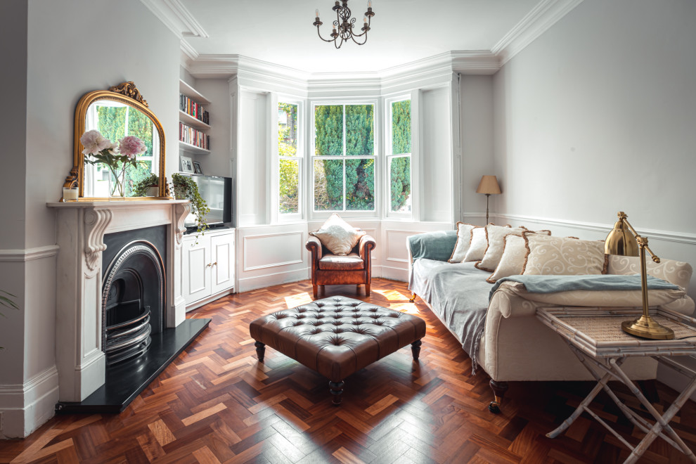 Immagine di un soggiorno classico chiuso con pareti grigie, parquet scuro, camino classico, TV autoportante e pavimento marrone