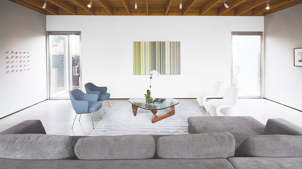 Idée de décoration pour un salon minimaliste avec sol en béton ciré et un mur blanc.