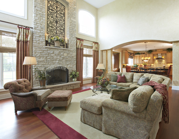 Elegant open concept medium tone wood floor living room photo in Chicago with beige walls, a standard fireplace and a stone fireplace