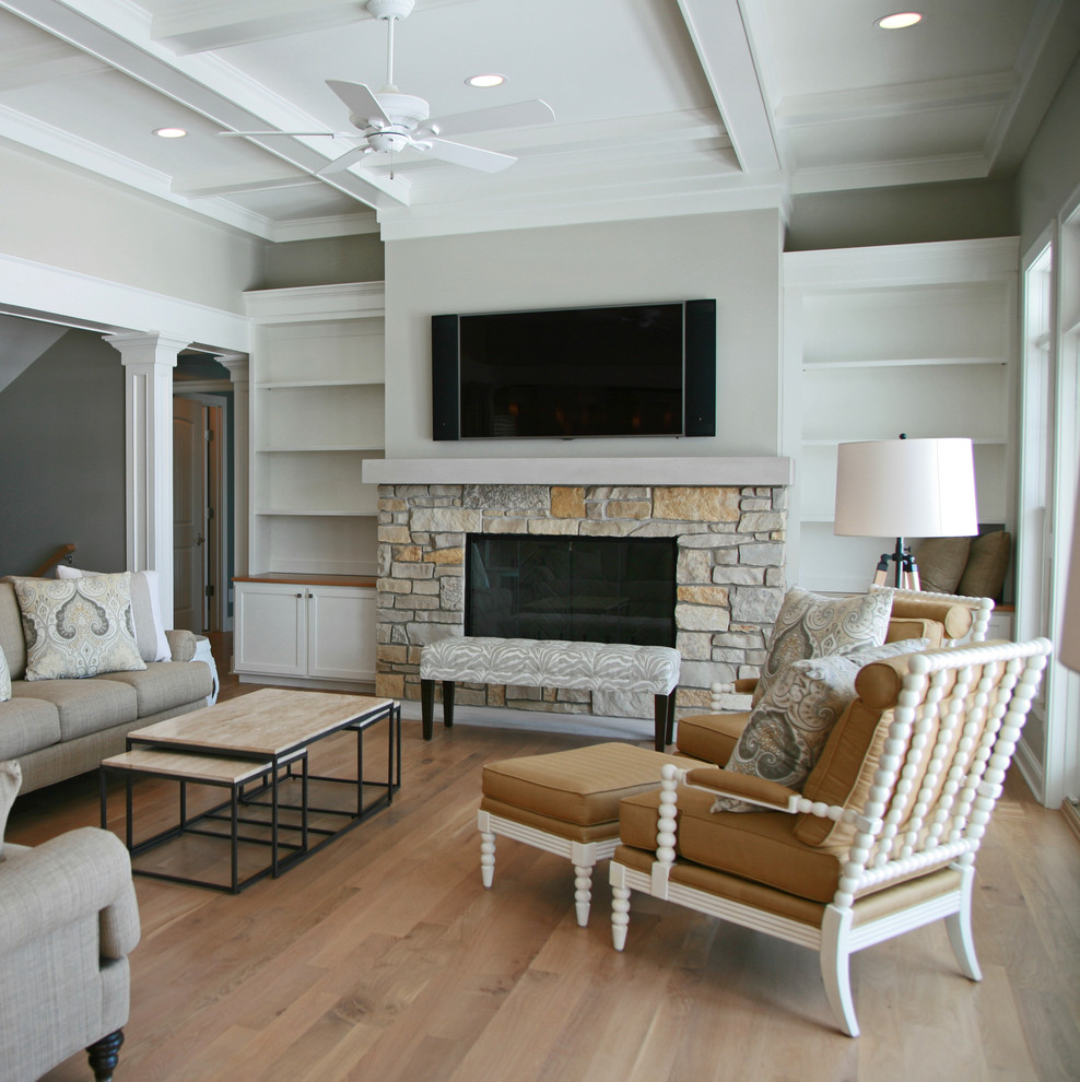 Aménagement d'un salon classique avec un mur gris, parquet clair, une cheminée standard, un manteau de cheminée en pierre et un téléviseur encastré.