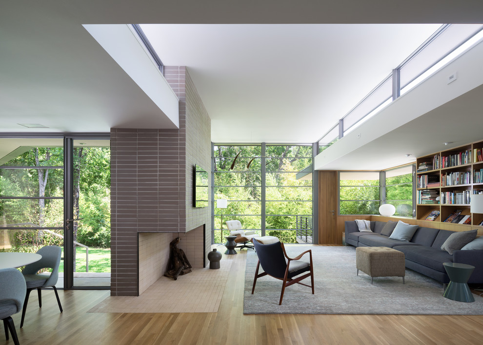 Offenes Retro Wohnzimmer mit hellem Holzboden, Eckkamin, Kaminumrandung aus Backstein, TV-Wand und braunem Boden in Austin