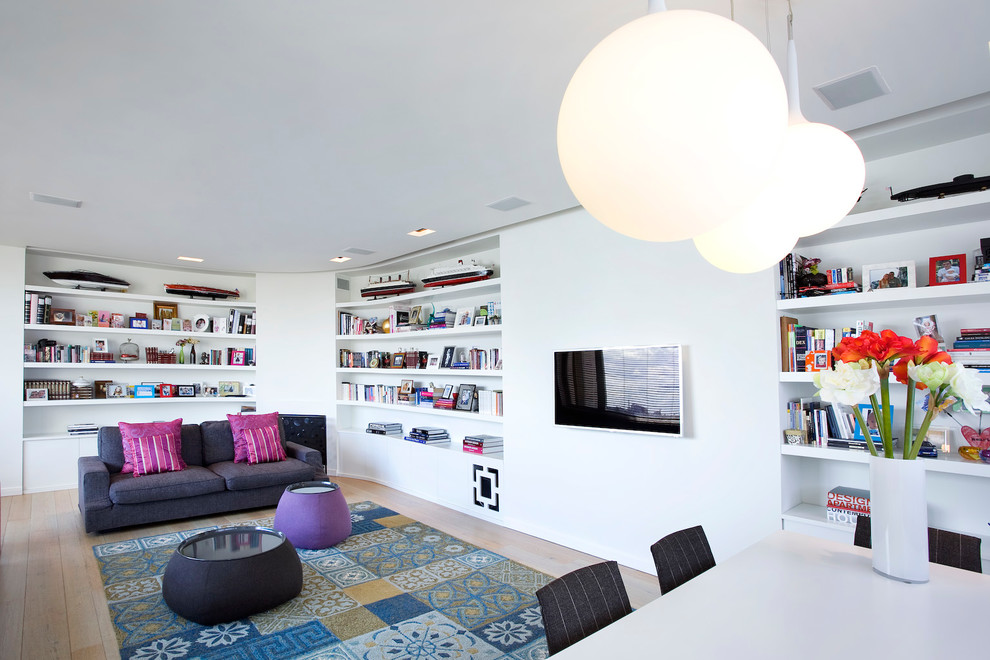 Cette photo montre un salon tendance avec une bibliothèque ou un coin lecture, un mur blanc, aucune cheminée et un téléviseur fixé au mur.