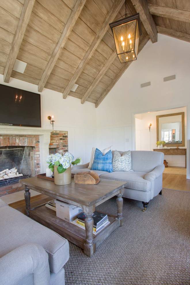 Design ideas for a traditional living room in Los Angeles with white walls, a standard fireplace, a brick fireplace surround and a wall mounted tv.